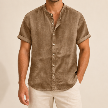 Model wearing a tan short-sleeve band-collar shirt with buttons down to the hem