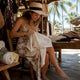 Woman folding linen shirt on tropical resort terrace