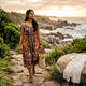 Woman in printed maxi dress on beach at sunset