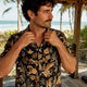 Man adjusting bold patterned Hawaiian shirt