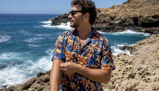 Man adjusting sleeve of Hawaiian shirt on beach