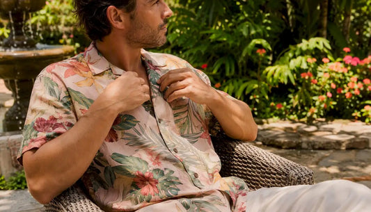 Man buttoning Dan Flashes natural-dyed Hawaiian shirt on patio