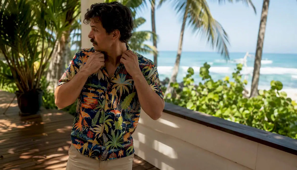 Man adjusting Hawaiian shirt on resort patio