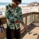 Man adjusting sleeve of tropical print shirt