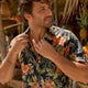 Man adjusting collar in Dan Flashes shirt on beach