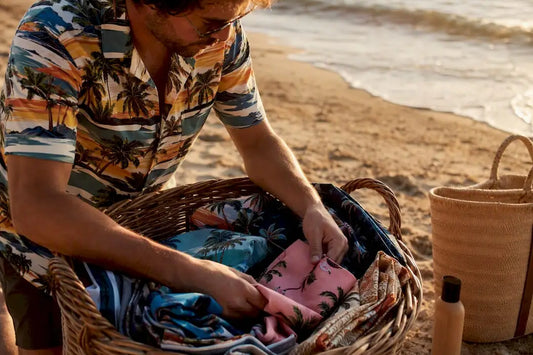 Man packing colorful tropical shirts into suitcase
