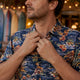 Man adjusting collar of Dan Flashes shirt on sunny patio