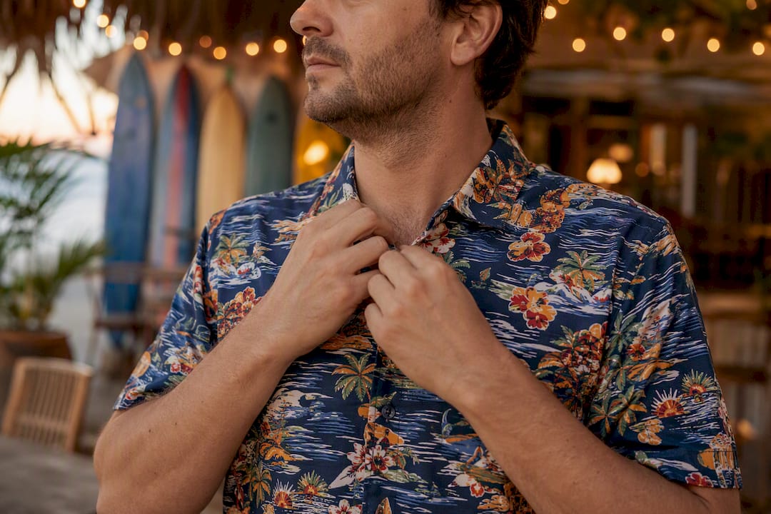 Man adjusting collar of Dan Flashes shirt on sunny patio