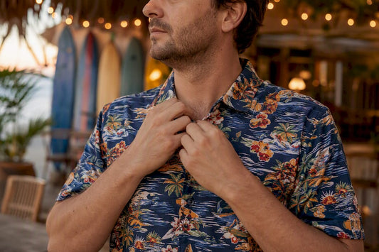 Man adjusting collar of Dan Flashes shirt on sunny patio
