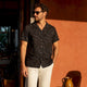 Man wearing dark patterned shirt in sunlight
