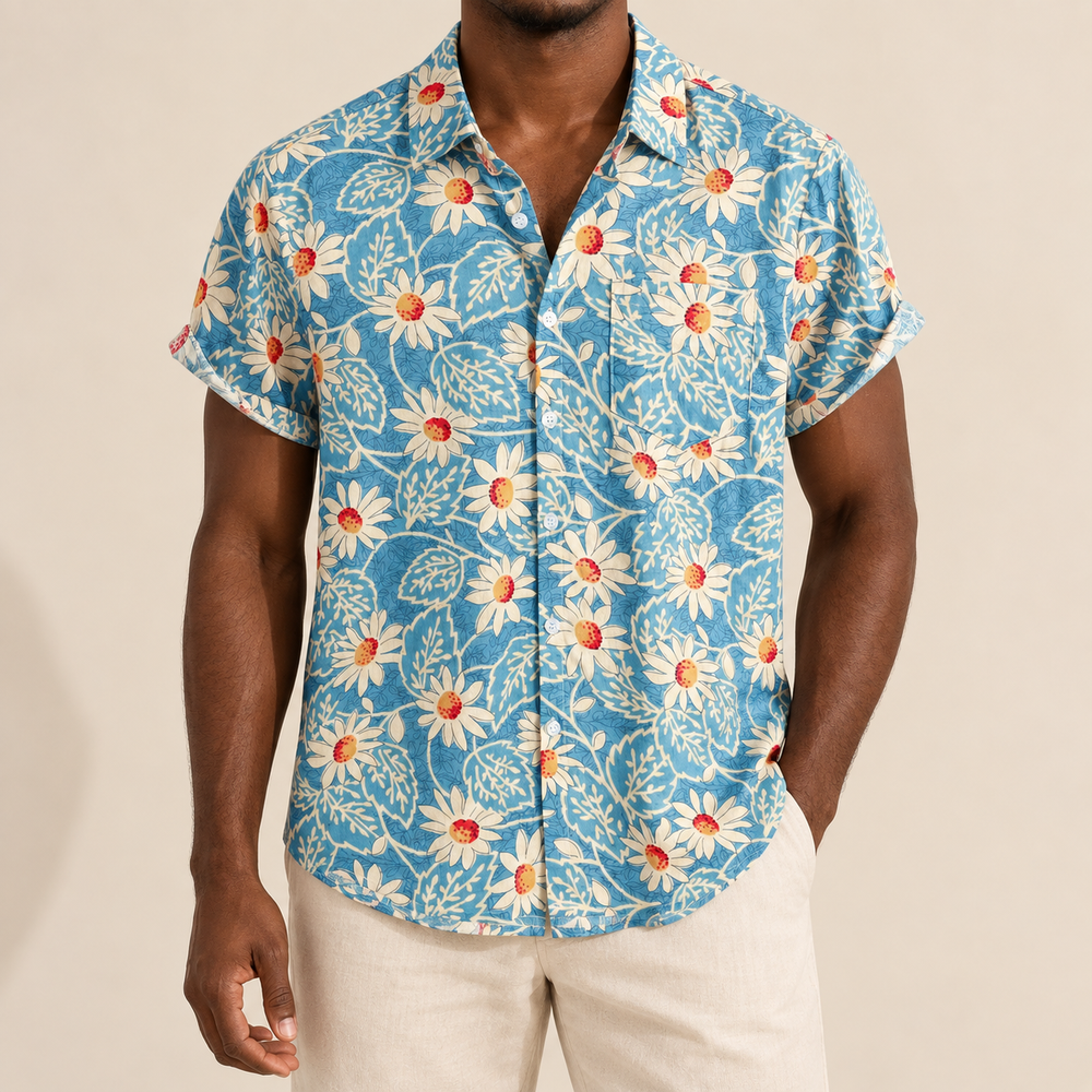 Model wearing blue short-sleeve resort shirt with pale daisy-like flowers and fine leaves