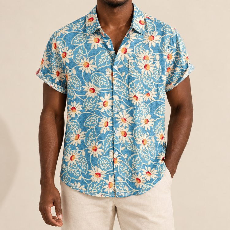 Model wearing blue short-sleeve resort shirt with pale daisy-like flowers and fine leaves