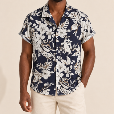 Model wearing a navy short-sleeve shirt with cream botanical flowers and leaves