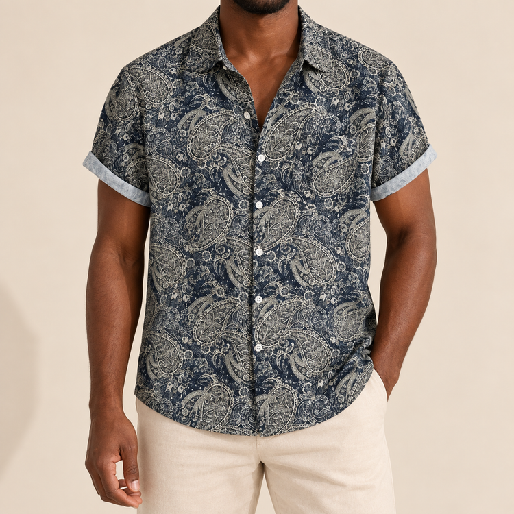 Model wearing dark short-sleeve button-up shirt with detailed pale paisley curls