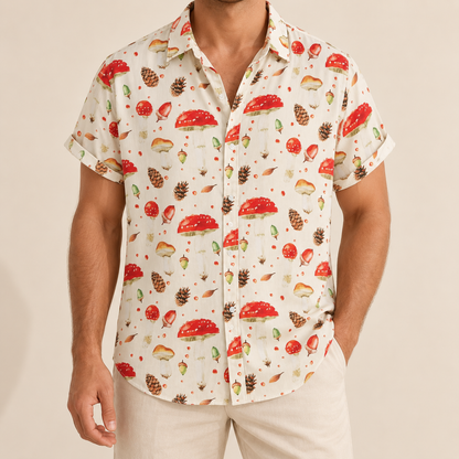 Model wearing an ivory button-up shirt with red mushrooms, pine cones and acorns