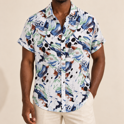 Model wearing a white short-sleeve shirt with blue and green painterly motifs