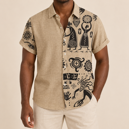Model wearing tan short-sleeve shirt with dark illustrated figures and symbols on one panel