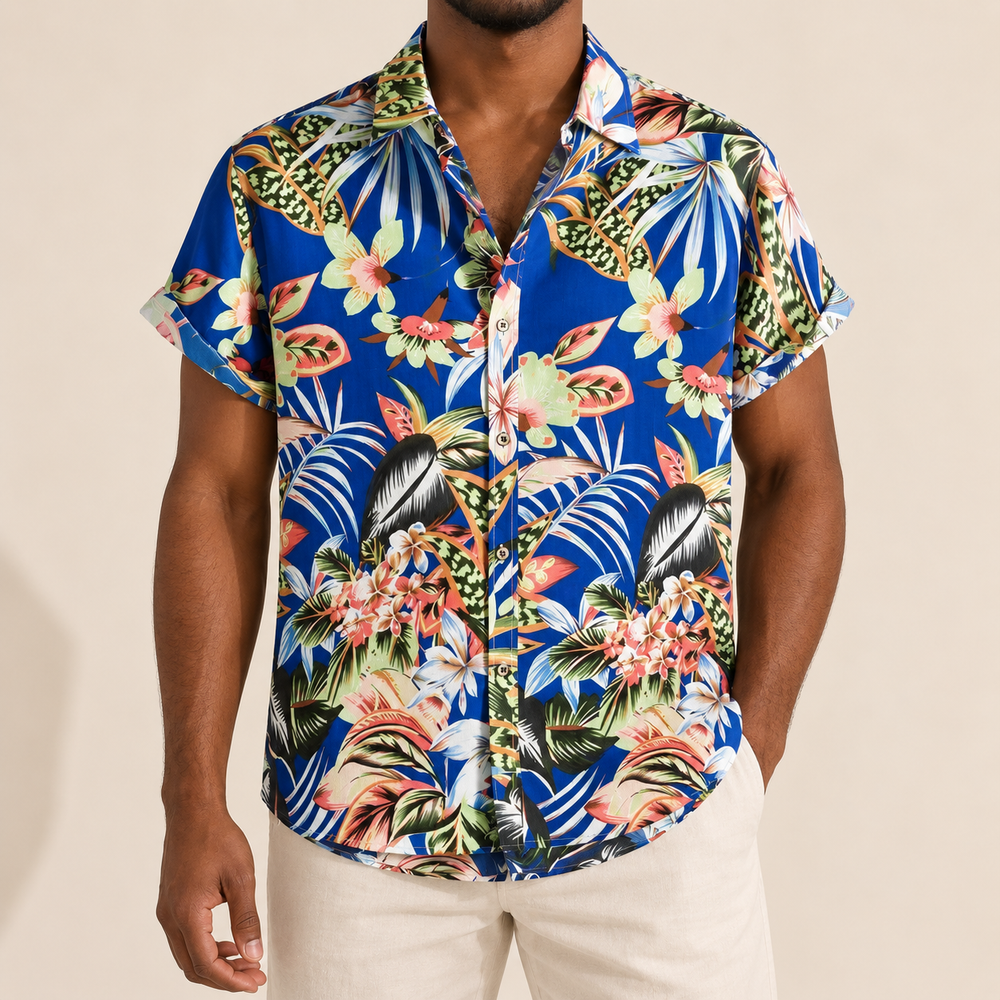 Model wearing a royal blue short-sleeve shirt with tropical flowers and leaves